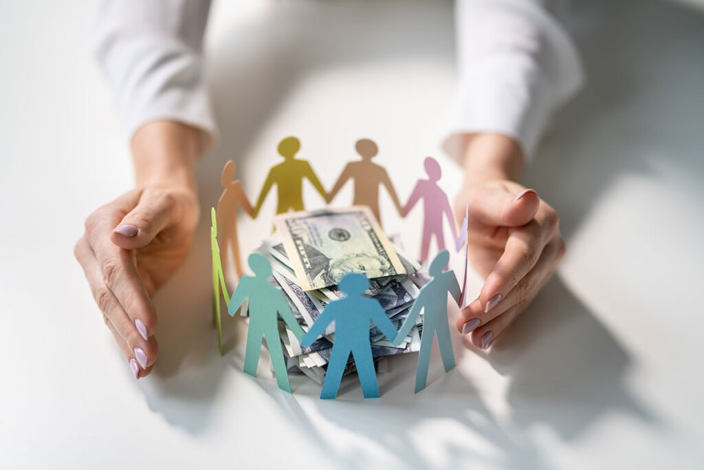 paper cutouts of people surrounding a pile of cash